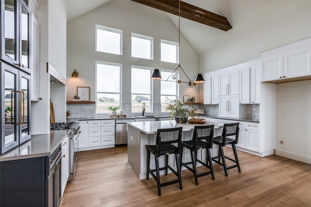 dining space with wood-type flooring, high vaulted ceiling, beamed ceiling, and a chandelier