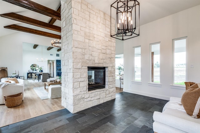 living room with a chandelier, a stone fireplace, and beamed ceiling