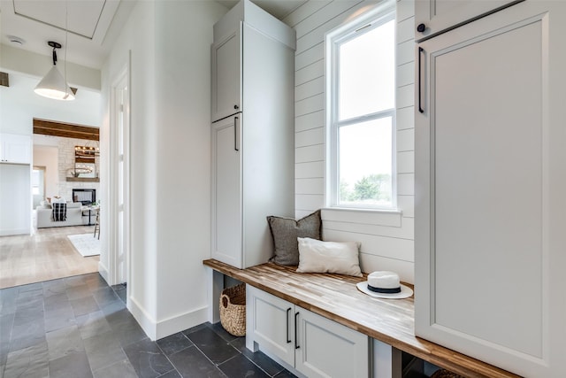 mudroom featuring a stone fireplace and wood walls