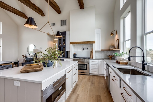 kitchen with sink, appliances with stainless steel finishes, backsplash, a center island, and white cabinets