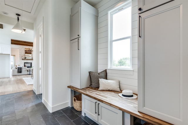 mudroom featuring a stone fireplace and wooden walls