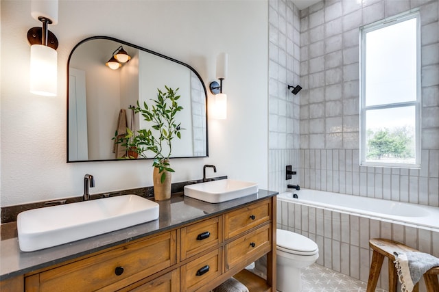 full bathroom with toilet, tiled shower / bath, and vanity