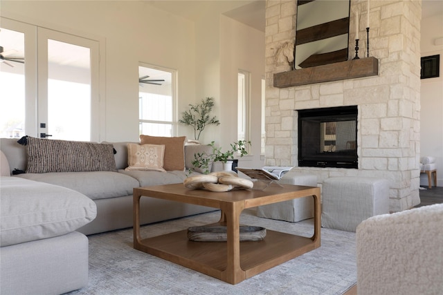 living room with a stone fireplace and ceiling fan