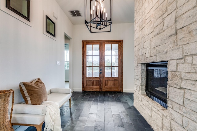 doorway to outside with dark wood-type flooring, a notable chandelier, french doors, and a fireplace