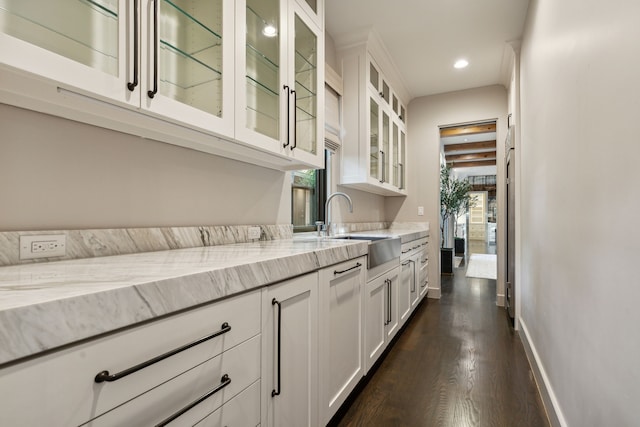 kitchen featuring sink, white cabinetry, light stone counters, and dark hardwood / wood-style floors