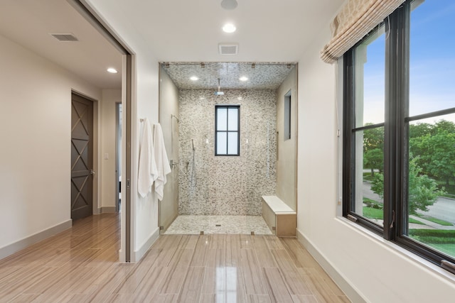 bathroom with a tile shower and wood-type flooring