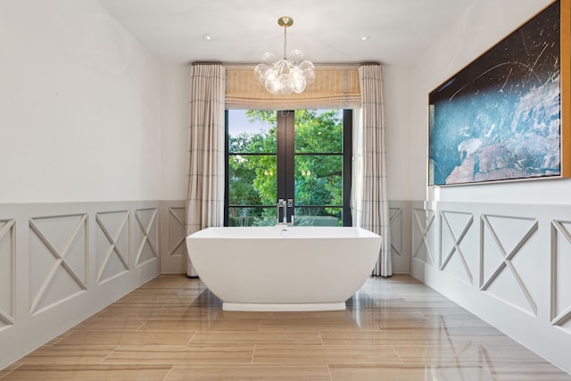 bathroom featuring french doors, a tub, a chandelier, and hardwood / wood-style floors