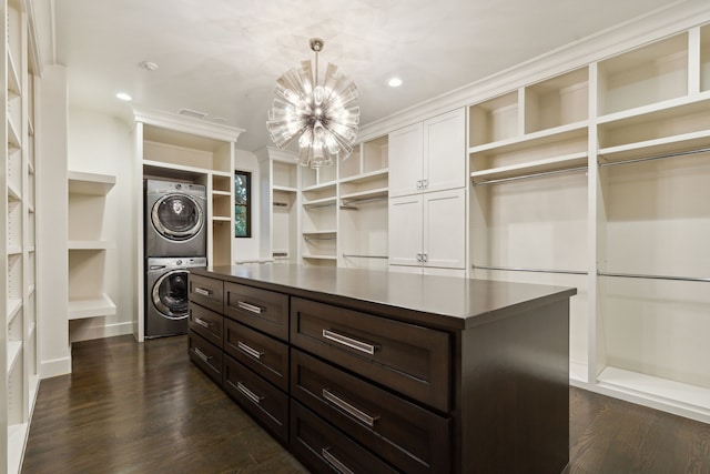 walk in closet featuring stacked washer / drying machine, a notable chandelier, and dark hardwood / wood-style floors