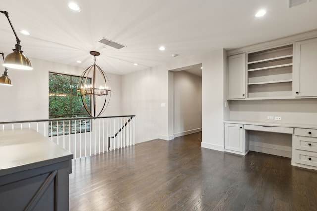 interior space featuring built in desk, a chandelier, and dark hardwood / wood-style floors