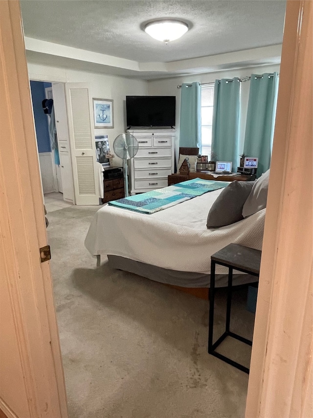 bedroom with a textured ceiling and light carpet