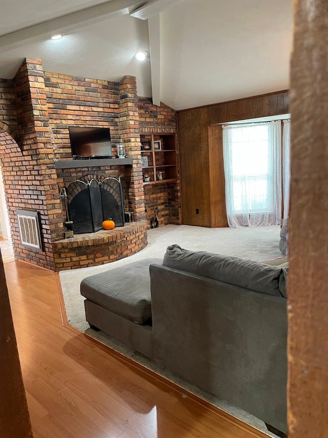 bedroom with wood-type flooring, vaulted ceiling with beams, and a brick fireplace