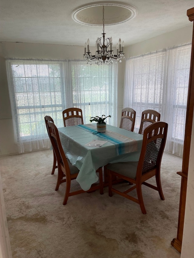 carpeted dining area featuring a wealth of natural light, a textured ceiling, and an inviting chandelier