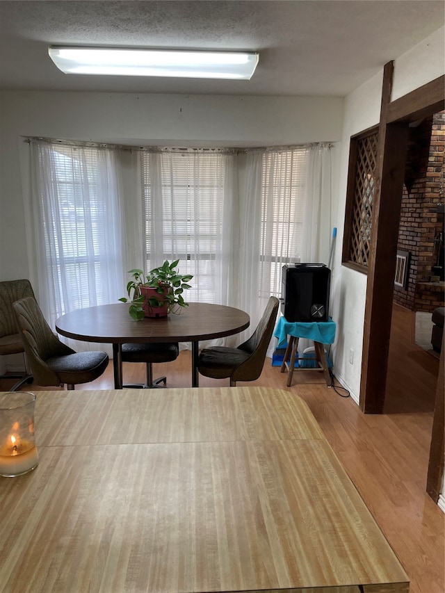 dining area with a textured ceiling, light hardwood / wood-style floors, and a fireplace