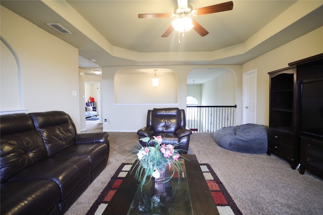 living room featuring carpet, ceiling fan, and a raised ceiling