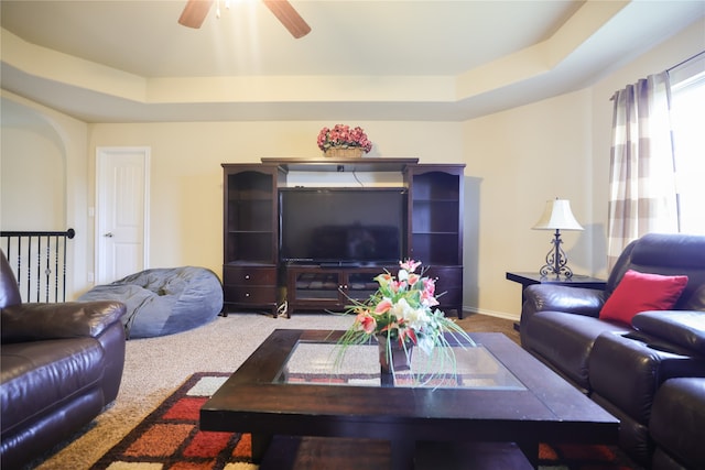 living room featuring carpet, a tray ceiling, and ceiling fan