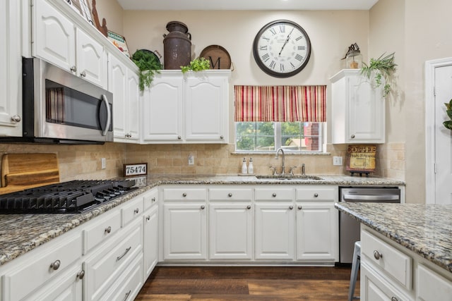 kitchen with sink, appliances with stainless steel finishes, white cabinetry, light stone counters, and tasteful backsplash