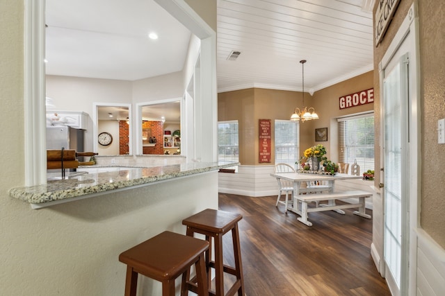 interior space with light stone counters, crown molding, hanging light fixtures, dark hardwood / wood-style floors, and a notable chandelier