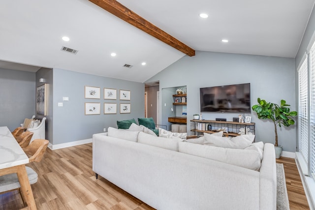 living room with vaulted ceiling with beams and light wood-type flooring