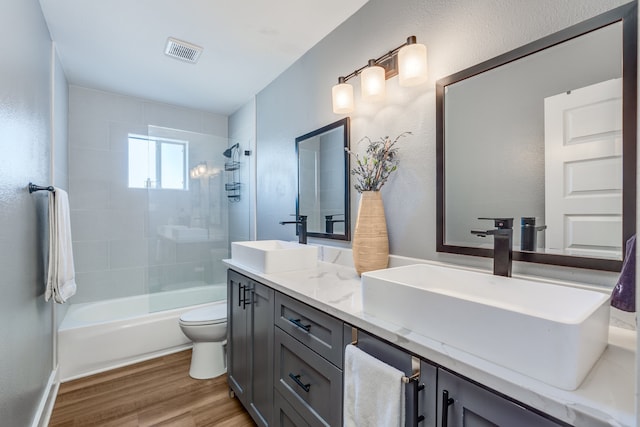 full bathroom featuring vanity, tiled shower / bath combo, wood-type flooring, and toilet