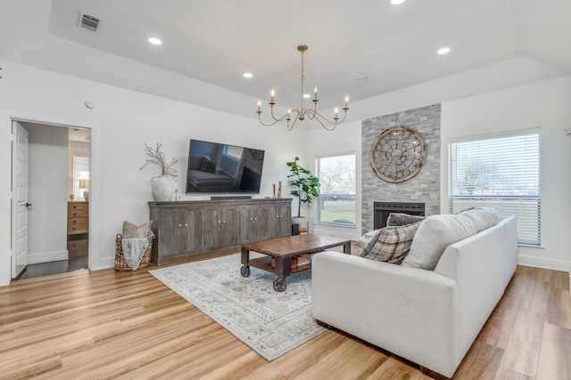 living room featuring a chandelier, a fireplace, light wood-type flooring, and plenty of natural light