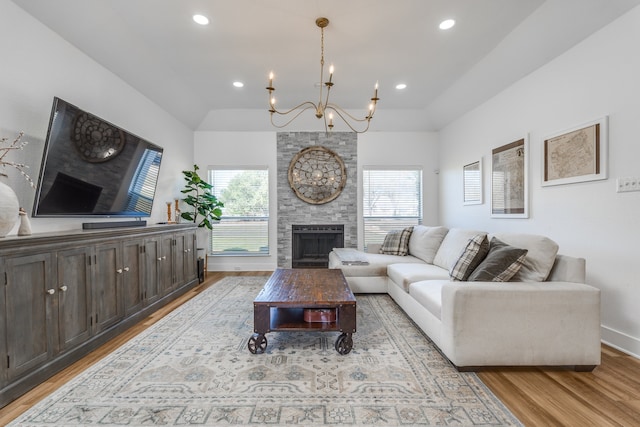 living room with an inviting chandelier, a fireplace, and light wood-type flooring