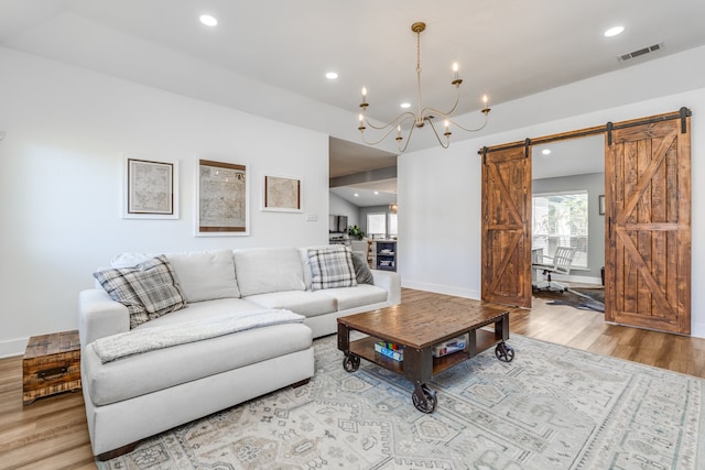 living room with light hardwood / wood-style floors, a notable chandelier, and a barn door