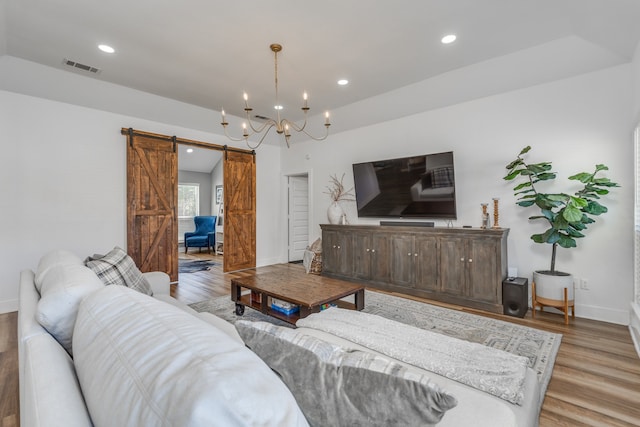 living room featuring light hardwood / wood-style flooring, a chandelier, and a barn door