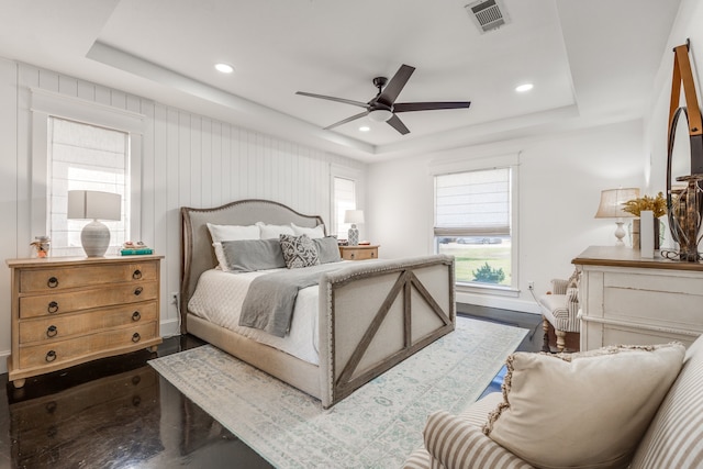 bedroom featuring dark wood-type flooring, a tray ceiling, and ceiling fan