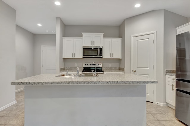 kitchen with sink, appliances with stainless steel finishes, white cabinetry, and an island with sink