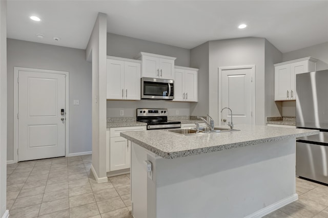 kitchen featuring a center island with sink, sink, white cabinets, light tile patterned floors, and appliances with stainless steel finishes