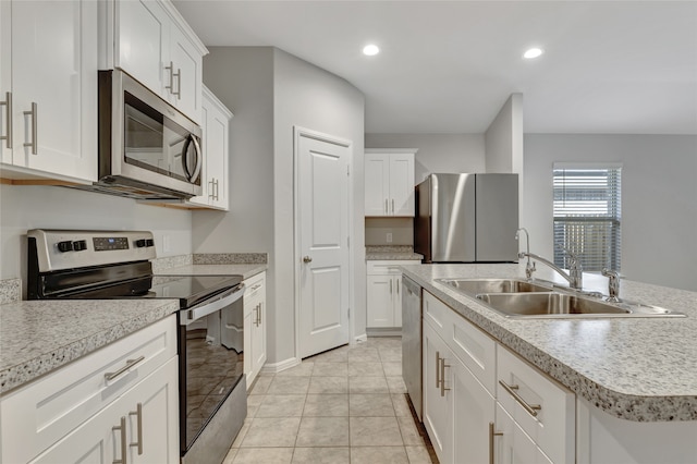 kitchen with white cabinetry, stainless steel appliances, sink, and a center island with sink