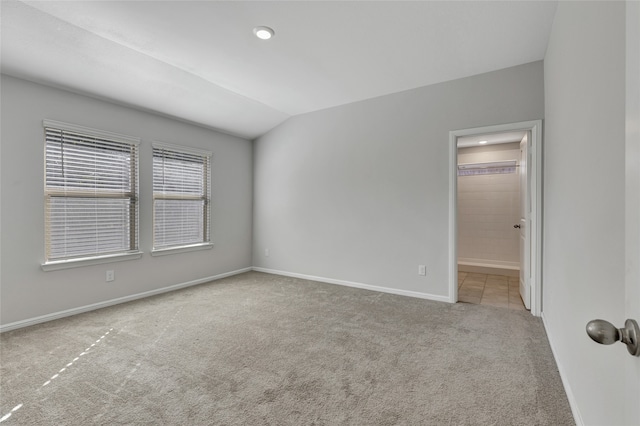 carpeted spare room featuring lofted ceiling