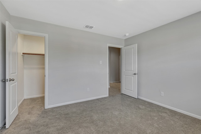 unfurnished bedroom featuring a spacious closet, light colored carpet, and a closet