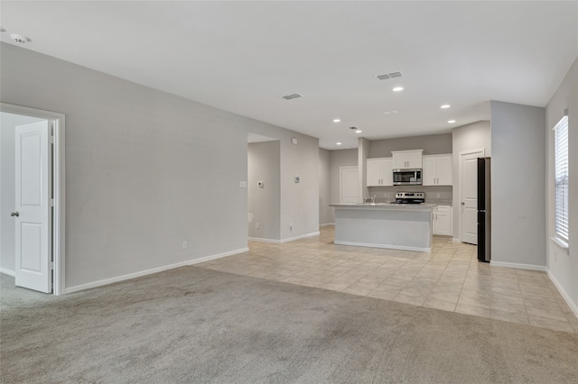 unfurnished living room featuring light colored carpet and sink