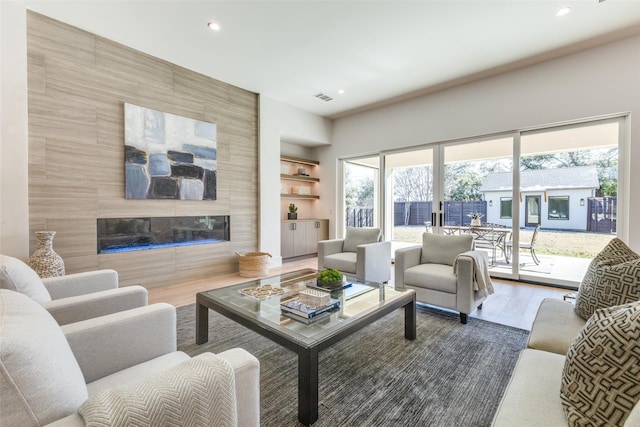 living room featuring a tiled fireplace, hardwood / wood-style floors, and tile walls