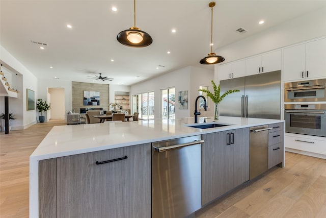 kitchen featuring a spacious island, white cabinets, hanging light fixtures, and appliances with stainless steel finishes