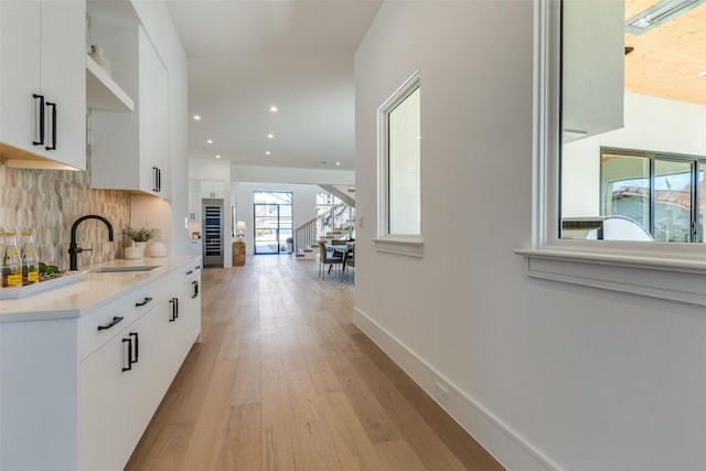 interior space with light hardwood / wood-style flooring, tasteful backsplash, white cabinetry, and sink