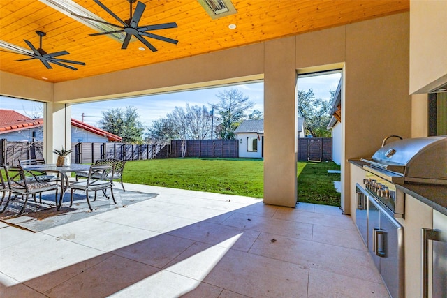 view of patio featuring grilling area, ceiling fan, exterior kitchen, and an outdoor structure