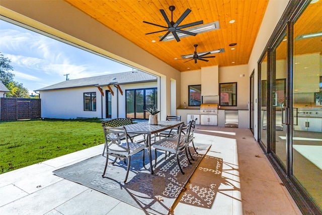 view of patio featuring ceiling fan, area for grilling, and exterior kitchen