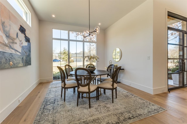 dining space with a chandelier, a high ceiling, and light wood-type flooring