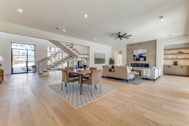 dining room with a fireplace, light hardwood / wood-style floors, and ceiling fan