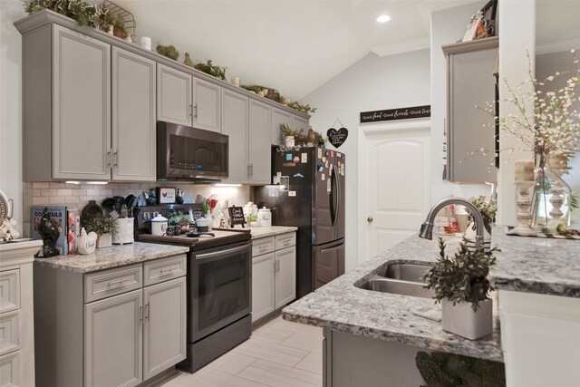 kitchen featuring appliances with stainless steel finishes, light stone countertops, sink, and gray cabinets