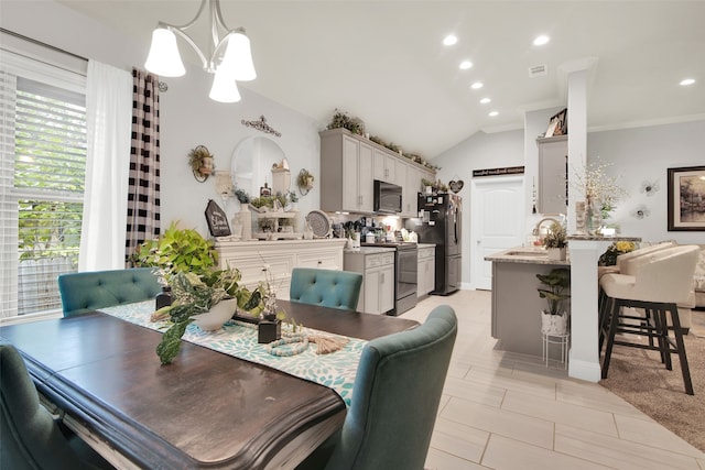 dining space with ornamental molding, a chandelier, sink, and vaulted ceiling