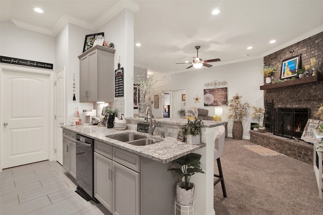 kitchen with a breakfast bar area, stainless steel dishwasher, sink, gray cabinetry, and light colored carpet