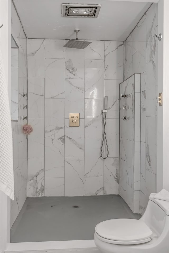 bathroom with a tile shower and toilet