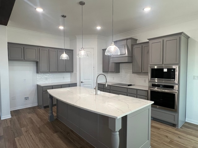 kitchen with appliances with stainless steel finishes, gray cabinets, and a kitchen island with sink