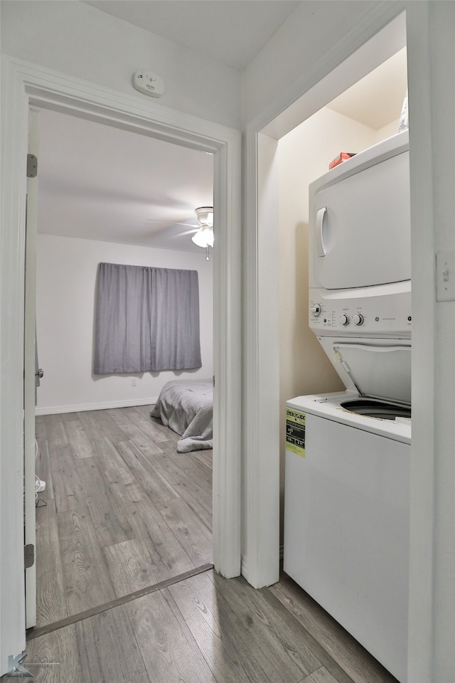 laundry area with stacked washer / drying machine, light wood-type flooring, and ceiling fan