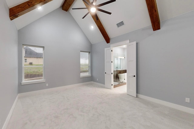 unfurnished bedroom with connected bathroom, beamed ceiling, and light colored carpet