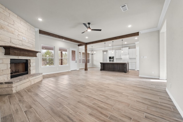 unfurnished living room with visible vents, ceiling fan with notable chandelier, and light wood-style floors