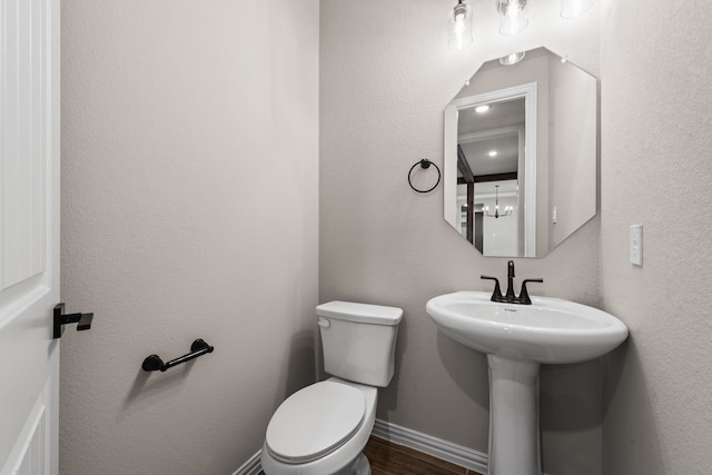 half bathroom featuring a sink, toilet, baseboards, and wood finished floors